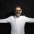 Fotografia di Massimo Bottura a braccia apertesu sfondo nero